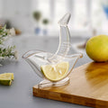 Hand holding the unique bird-shaped manual juicer over a glass.