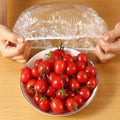 An elastic food cover keeping a plate of sliced fresh fruits perfectly sealed.
