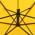 A close-up view of the black metal frame and ribs supporting the bright yellow fabric of an open umbrella.