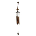 Side view of metal wind chime with Om symbol against green background
