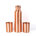 A person pouring water from the leakproof copper bottle into one of the matching glasses.