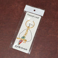 Side angle of Krishna flute keychain with peacock feather design in metal