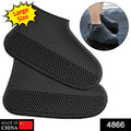 A person's feet wearing black silicone shoe covers stand on a wet wooden deck.