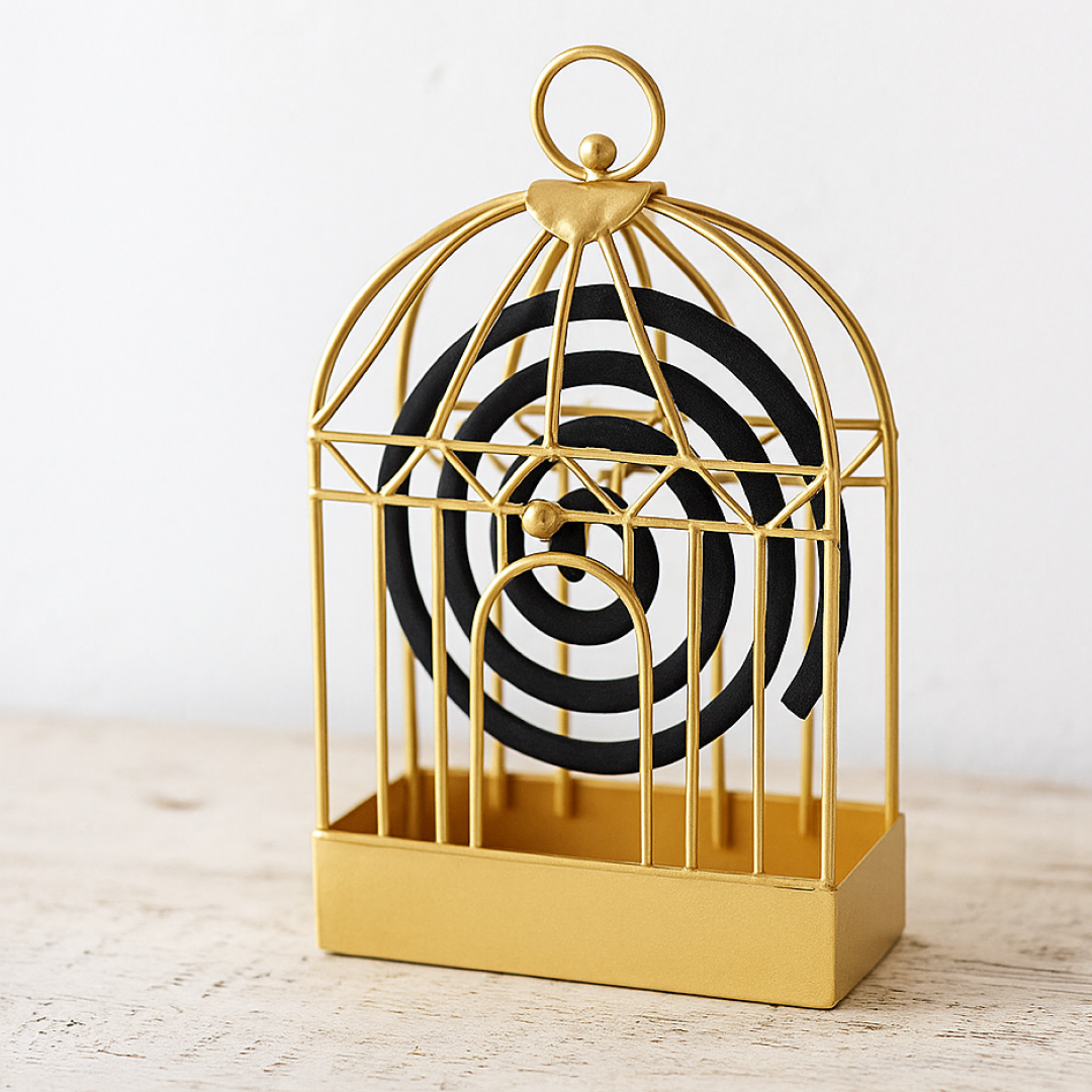 A black iron birdcage-style holder with a burning mosquito coil inside sits on a light wooden table.