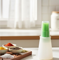 Silicone oil dispenser brush applying oil evenly on a hot cooking pan.