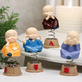 Baby monk figurines displayed on a car dashboard