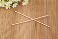 A hand holding a bamboo BBQ skewer with various ingredients for grilling.
