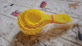 A perfectly shaped ladoo sits next to the plastic mould spoon used to create it.