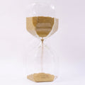 Close-up of yellow sand flowing smoothly in a glass hourglass timer.