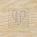 Close-up of transparent wall hook showing its adhesive pad