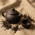 Traditional ceramic teapot pouring tea in a matte black finish