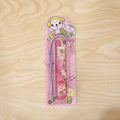 Pink stationery set displayed in use, showing ruler, pencil, eraser, and sharpener.