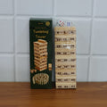Family members gathered playing the Tumbling Tower wooden block game