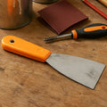 A BoltForce putty knife being used to smooth a surface during a home improvement project.