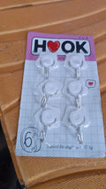 A collection of colorful adhesive hooks demonstrating various uses in a home setting.